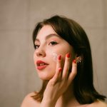 woman with flawless skin applying facial cream