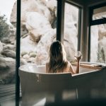 woman in a tub drinking wine on a self care day at home