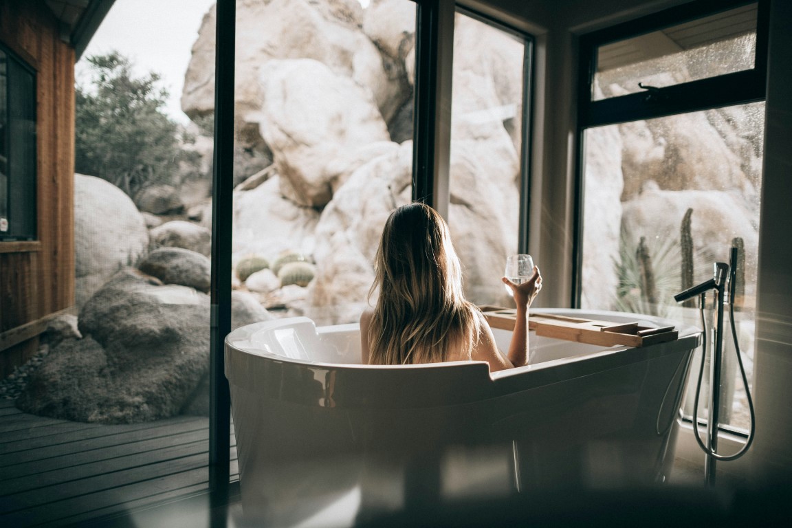 woman in a tub drinking wine on a self care day at home