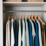 A simple, organized closet with a few high-quality, versatile clothing items neatly arranged on wooden hangers