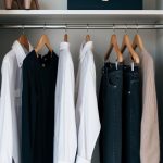 A closet with classic pieces: a white button-up shirt, a little black dress, a tailored blazer, dark denim jeans, and a neutral cashmere sweater